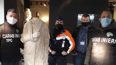 Gli ufficiali dei Carabinieri (polizia paramilitare italiana) dell'unità di archeologia del team artistico posano con una statua romana senza testa che indossa una toga rovesciata a Bruxelles. 