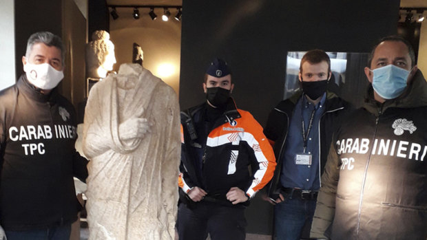Carabinieri (Italian paramilitary police) officers of the art squad’s archaeological unit pose with a headless Roman statue wearing a draped toga in Brussels. 