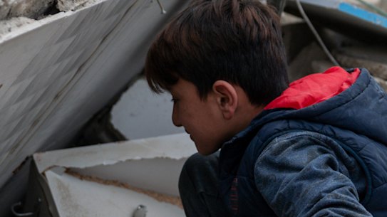 A child searches for kitchen tools inside of the debris of a building that has collapsed after an IDF airstrike on March 18, 2026 in Beirut.