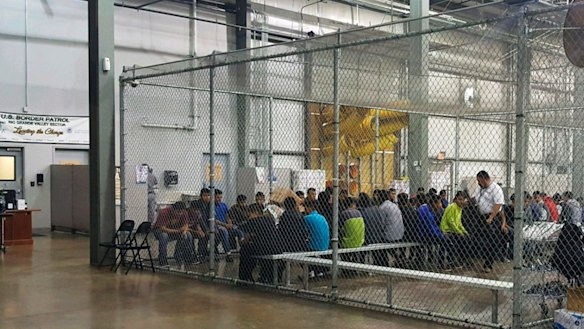 In this photo provided by U.S. Customs and Border Protection, people who've been taken into custody related to cases of illegal entry into the United States, sit in one of the cages at a facility in McAllen, Texas, Sunday, June 17, 2018. 