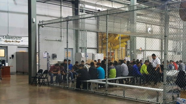 In this photo provided by U.S. Customs and Border Protection, people who've been taken into custody related to cases of illegal entry into the United States, sit in one of the cages at a facility in McAllen, Texas, Sunday, June 17, 2018. 