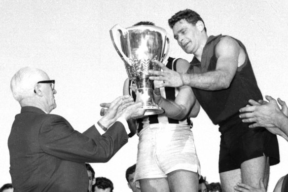 Melbourne captain Ron Barassi receives the 1964 VFL premiership cup from Sir Kenneth Luke.