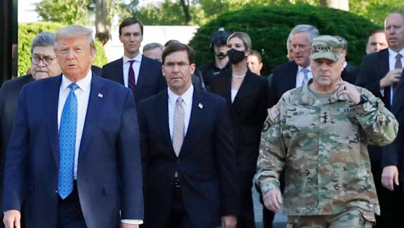 Trump's controversial use of troops to clear protesters in June. Trump postures with Chair of the Joint Chiefs of Staff, General Mark Milley, then-secretary of defence Mark Esper is in the middle.