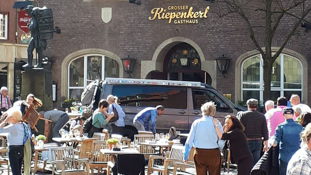 People stay in front of a restaurant in Muenster, Germany, on Saturday after a vehicle crashed into a crowd killing two people and injuring 20 others. 