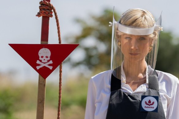 Elizabeth Debicki as Princess Diana visiting minefields in Bosnia with a badge of a New Zealand-based charity called ReliefAid.