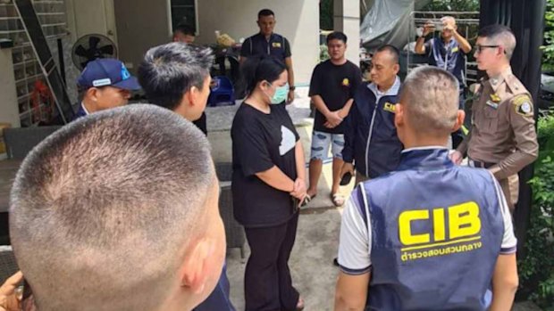 Wilawan “Golf” Emsawat (wearing face mask) during her arrest at her home in Nonthaburi on Tuesday. 