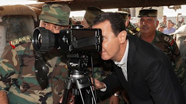 Syrian President Bashar al-Assad, centre, uses a military telescope during a visit to a strategic town in Idlib province last week. 
