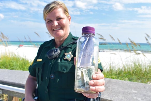 Sergeant Paula Pendleton of the Walton County sheriff's office with a bottle containing a man's ashes which was handed in to police after washing up on a Florida beach.