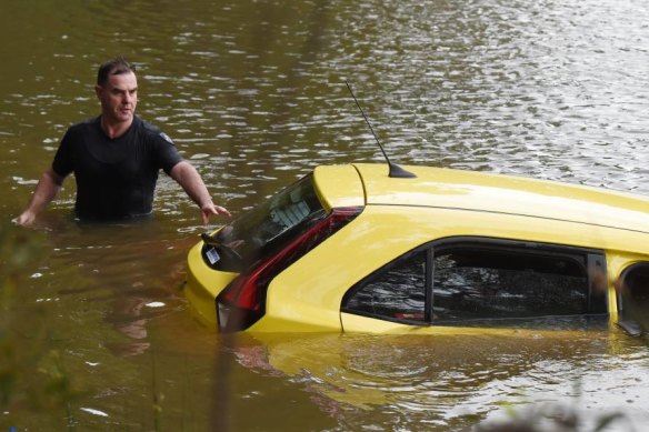 Leading Senior Constable Simon Barker helps secure the car as it is removed from O'Keefes Dam.