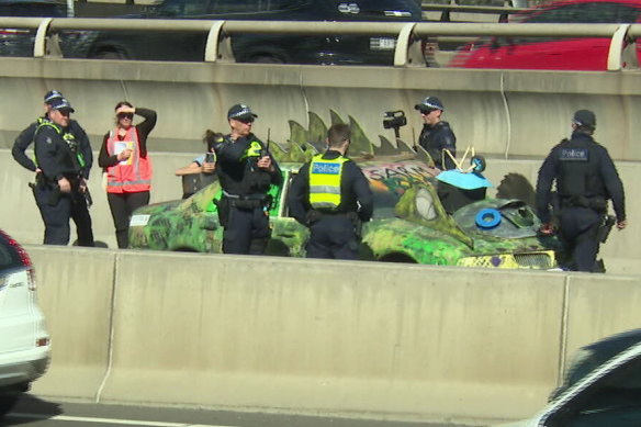 An anti-war demonstrator “affixed” herself to a car during a protest on the West Gate Freeway.