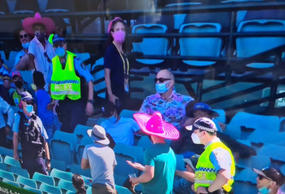 Ben Grogan, wearing sunglasses and a Hawaiian shirt, watches on as police remove spectators from the SCG on Sunday.