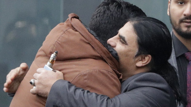 Abdul Aziz, centre, a survivor of the Linwood mosque shootings, is embraced by friends outside the Christchurch District Court.