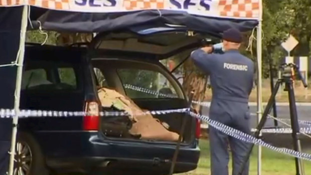 Forensic police examine boot of car.