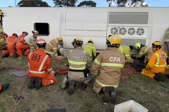 Firefighter Reg Stott holds his hand up to let the crew know the bus had been lifted high enough off the ground. 