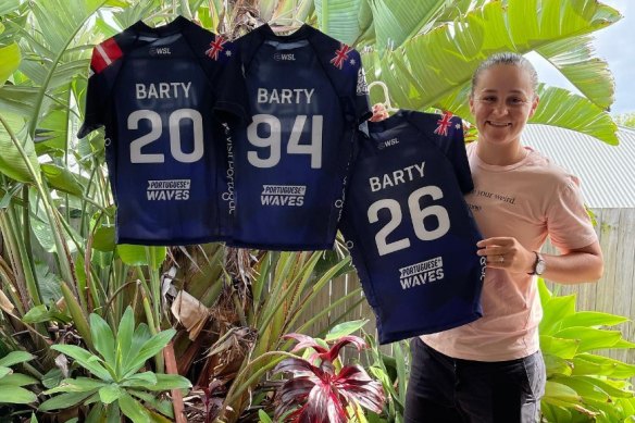 Ash Barty at home with the competition rash vests worn by Australian surfers Molly Picklum, Bronte Macaulay and Isabella Nichols in Portugal.