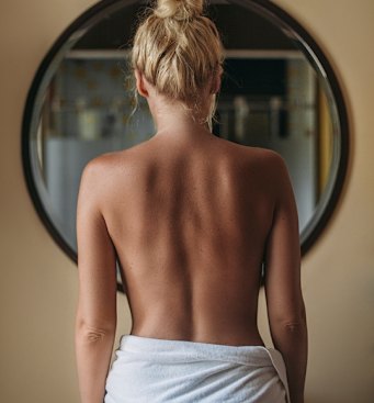 Blonde woman standing in front of the bathroom mirror in the morning.