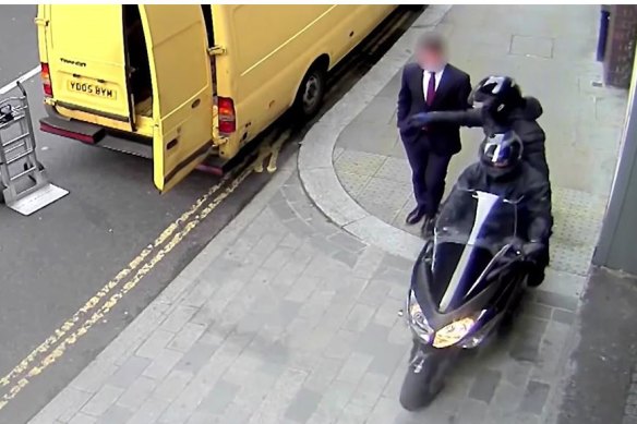 A thief steals a mobile phone from a man walking down a London street.