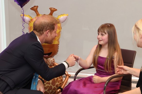 Prince Harry visits with a young person at the WellChild charity event.