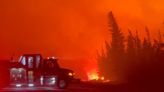 A vehicle is parked near a burning wildfire in Hay River, Canada, this week.