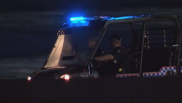 Police search the shoreline at Broadbeach on Thursday night after a woman’s body washed up.