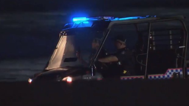 Police search the shoreline at Broadbeach on Thursday night after a woman’s body washed up.