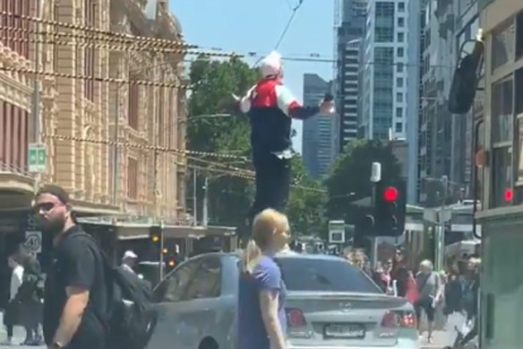 A man allegedly did doughnuts and climbed onto the top of his car on the corner of Flinders Street and Swanston Street.
