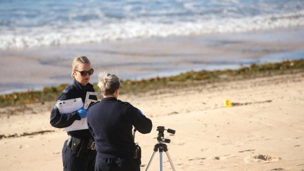 Police officers conduct an investigation on Stockton Beach.