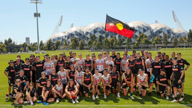 Collingwood players and staff with the Aboriginal flag.