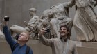 Visitors pose in front of the British Museum's Elgin Marbles that originate from the Parthenon in Athens.
