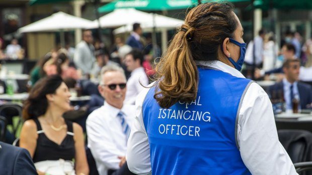 A social distancing officer patrols the Everest Race Day at Royal Randwick Racecourse on October 17, 2020 where almost 11,000 people gathered following approval of COVID-safe plans. 