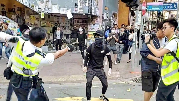 In this image from a video, a Hong Kong policeman holds on to one protester and prepares to shoot at another one, who was later hospitalised. 