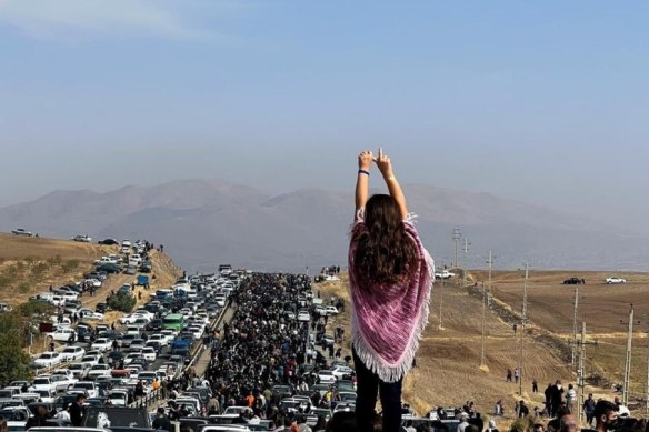 A girl with uncovered head stands atop a car during protests in Iran.