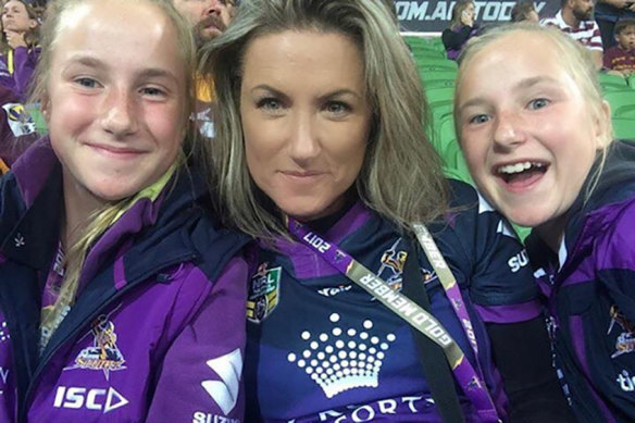 Melbourne Storm fan Samantha Humphrey flanked by her twin daughters at a game.