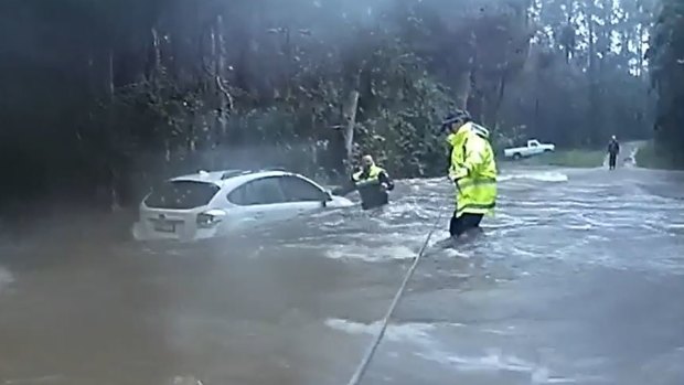 The woman became trapped in neck-high water after her car was swept away by floodwaters.