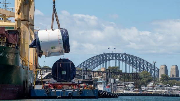 A part of the tunnel boring machine named Kathleen is lifted onto a barge from a ship at White Bay.
