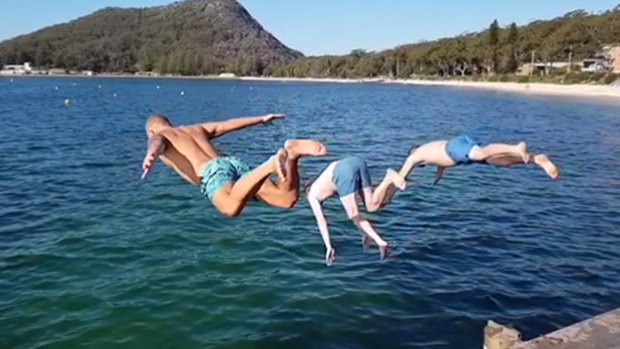 Ash Treseder, left, dives from the pier at Shoal Bay with friends in April last year.