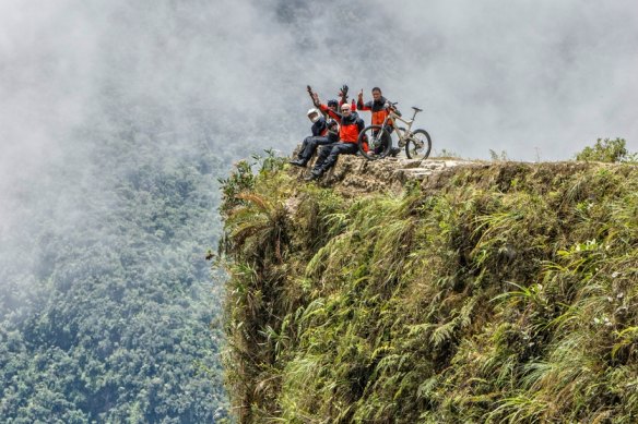 The only way is down: mountain bikers at a viewpoint of the famous downhill trail “Road of death” in Bolivia.