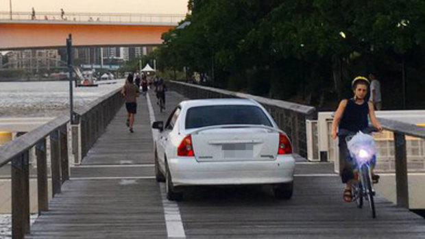 Pedestrians watch on as police stop a car on the South Bank pedestrian boardwalk near the Kurilpa Bridge.