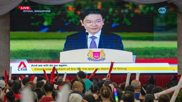 Attendees watch a broadcast of the swearing-in ceremony of Prime Minister Lawrence Wong in Singapore, on Wednesday evening.