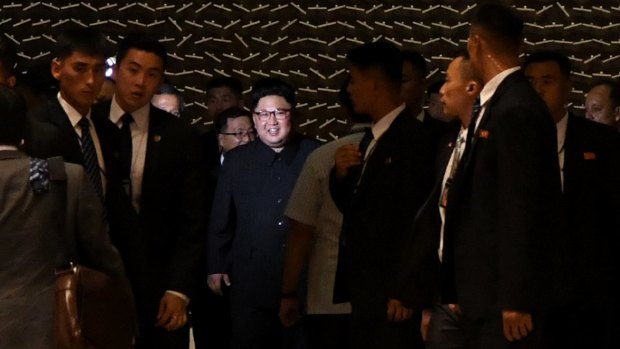 Kim arrives at the Marina Bay Sands in Singapore, his face lit by a camera making a propaganda film about his visit.
