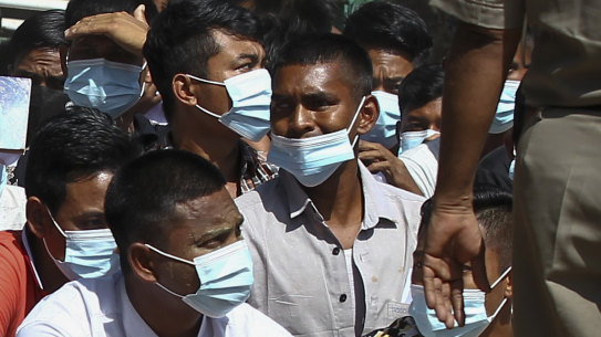 Security forces in Myanmar stand guard over detainees in February.