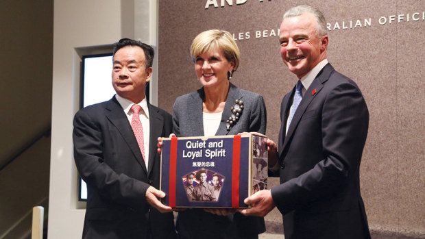 Chinese-Australian businessman Chau Chak Wing, Foreign Affairs Minister Julie Bishop and Australian War Memorial director Brendan Nelson holding the cover imagery of the book stocked in the War Memorial gift shop.