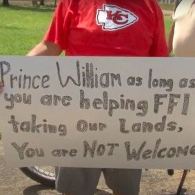 A protesters holds a sign criticising the Prince.