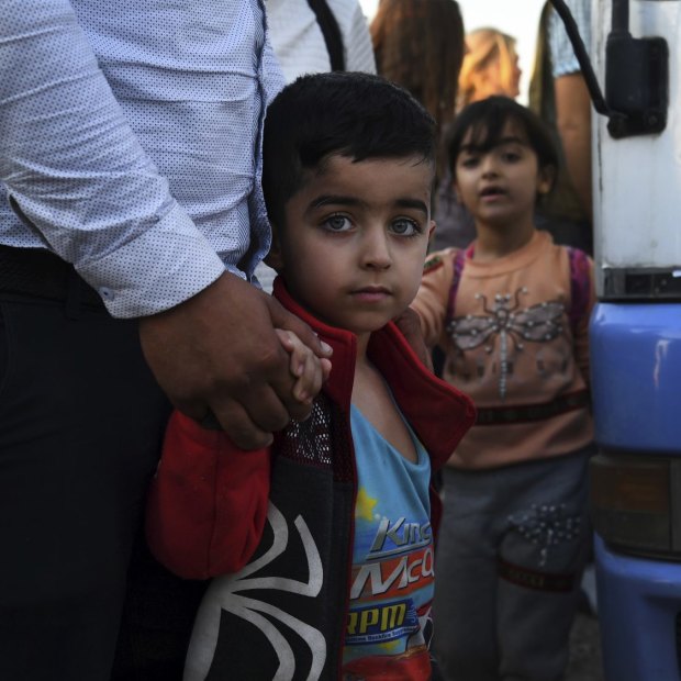A Syrian boy holds his father's hand after disembarking from one of the buses that brought 784 Syrian refugees to Bardarash Refugee Camp in Iraqi Kurdistan.
