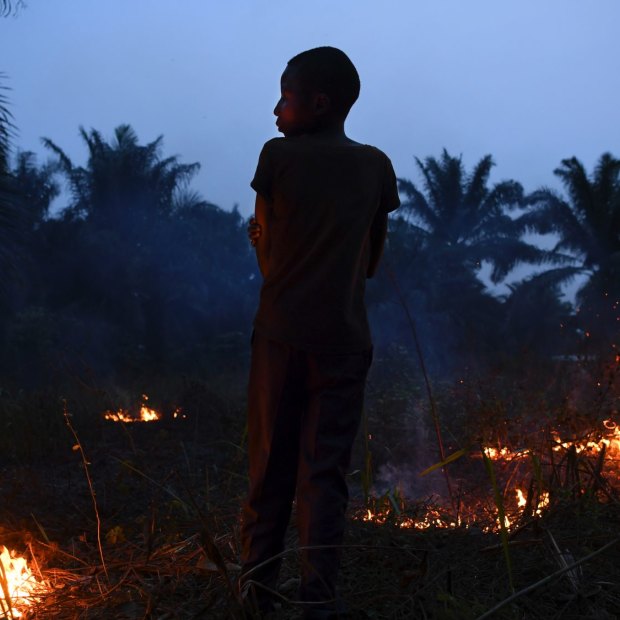 Former child soldier Wilson, 15 years old, watches over a small fire in his village in Kasai Central.