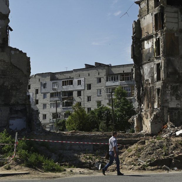A man walks past the ruins of an apartment building complex destroyed by a Russian missile strike in Borodyanka.
