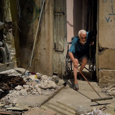 Abdulsalam Abdulqadir, 73, sweeps outside his gate from his wheelchair as an airstrike hits nearby in West Mosul, Iraq, in October 2017.