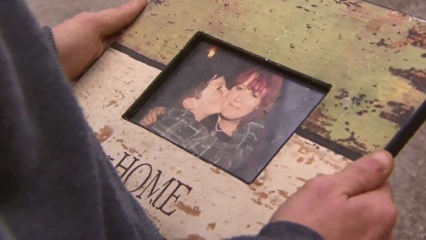 Harley holds a photo of himself with his mother.