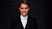 After Prince George arrived, he got into his school uniform, which is a formal suit with pinstripe trousers and coattails on the jacket, paired with a white tie.