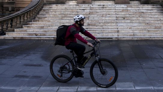 A delivery rider passes the City of Sydney Town Hall.